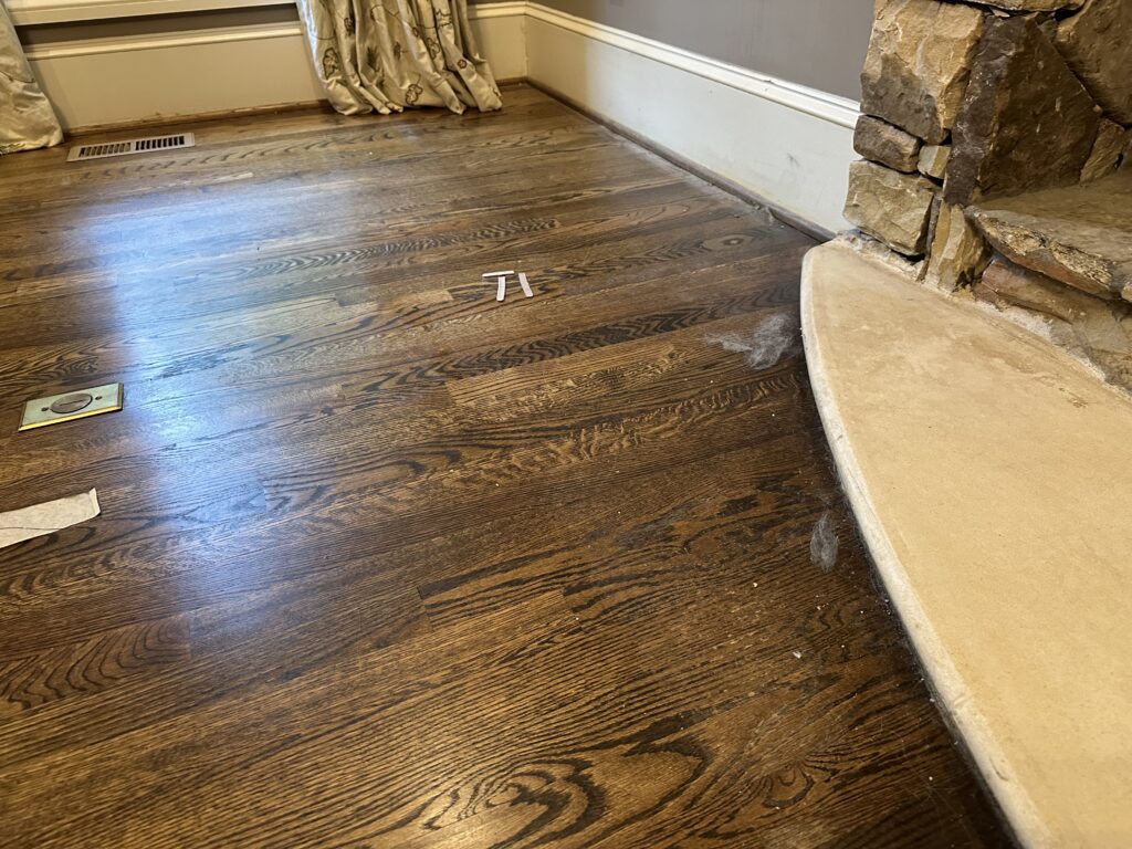 Professional move-in cleaning in Smyrna GA showing an immaculate empty living room with vacuumed carpet, freshly wiped baseboards, clean windows, and a woman in uniform dusting a light fixture.